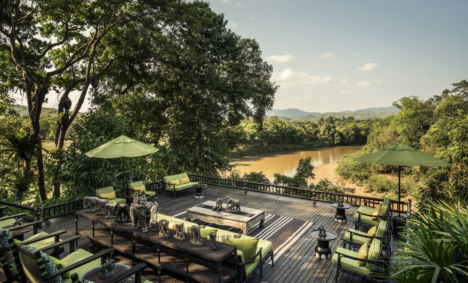 Terrace with plush patio chairs and elephant statuary overlooking the river at Four Seasons Tented Camp Golden Triangle