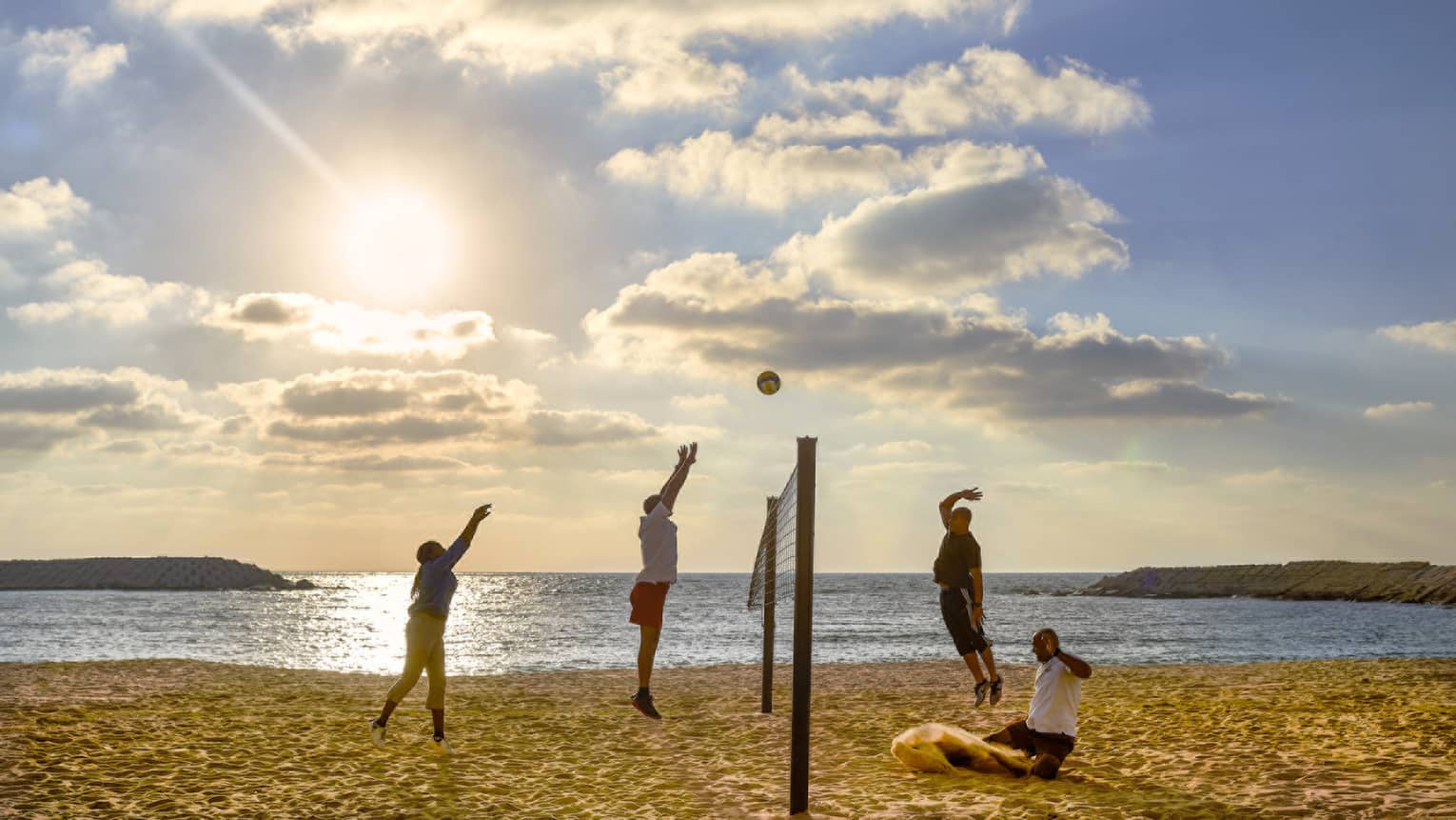A group of four play volleyball on the beach at four seasons hotel alexandria.
