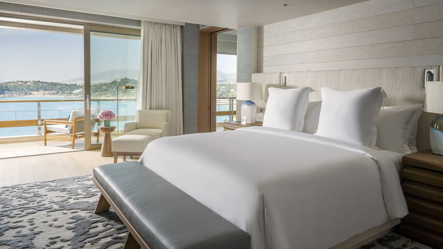 Arion Sea View Suite with white bedding, balcony with chairs overlooking ocean