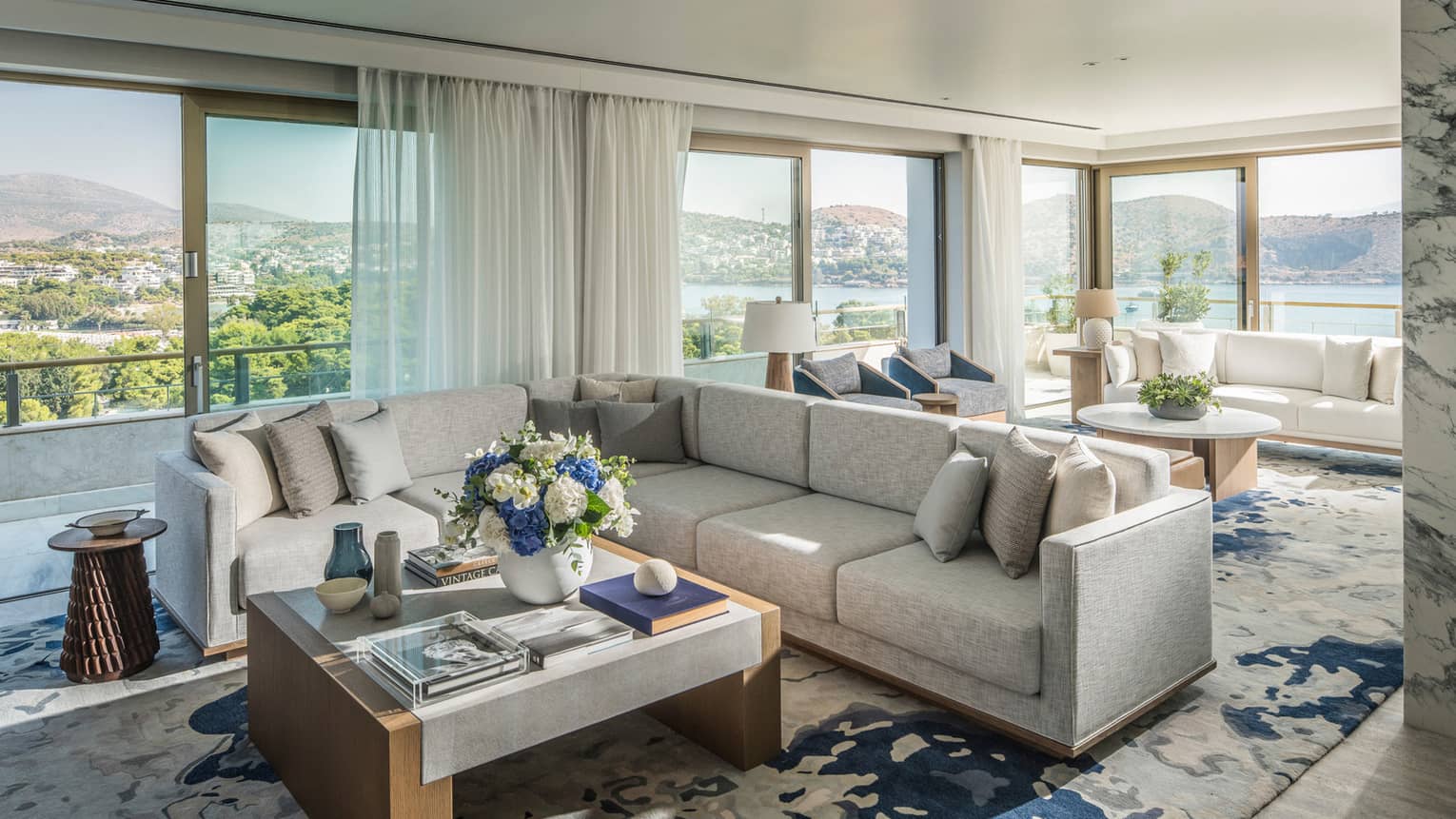 Arion Riviera Suite living area with white sectional sofa, square coffee table, patterned area rug, panoramic ocean views