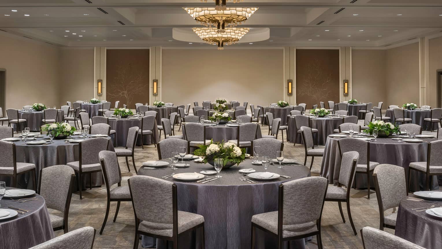 Round banquet tables with grey linens, chairs in ballroom