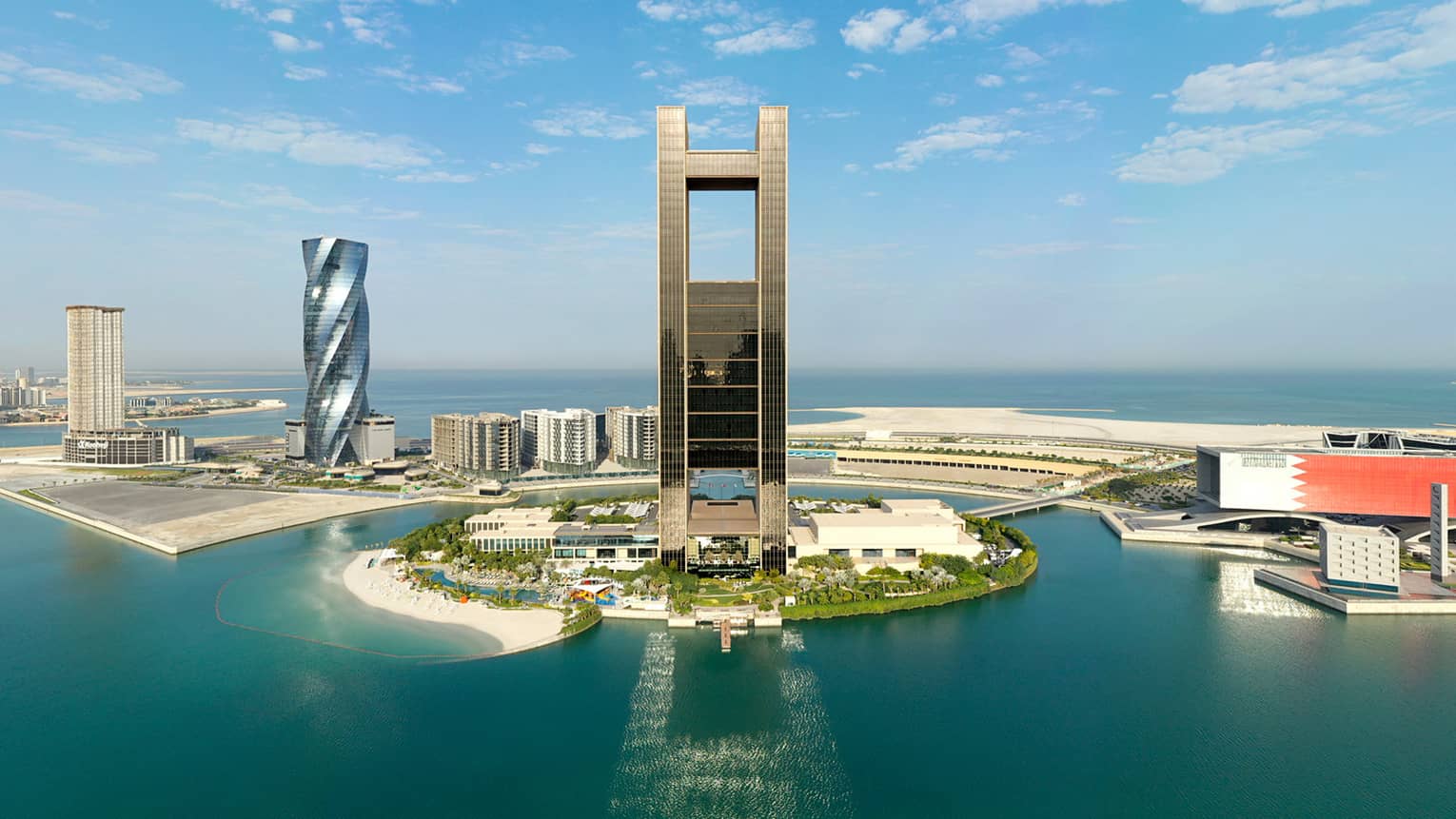 A drone shot of the Four Seasons Bahrain Property showcasing the sea and the large frame of the hotel's facade.