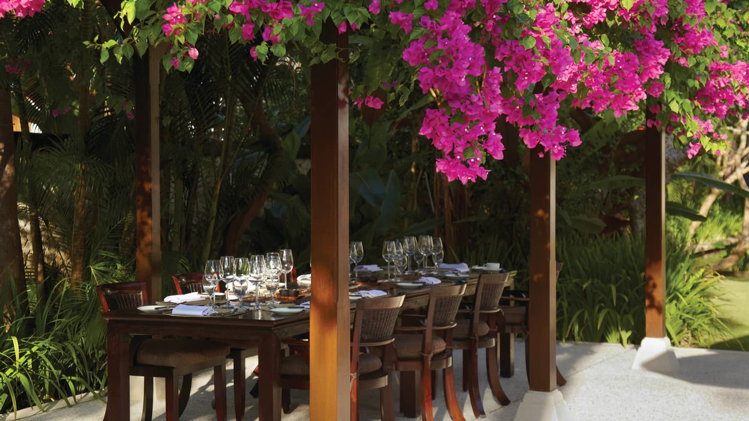 Purple flowers draped over pergola and large outdoor dining table