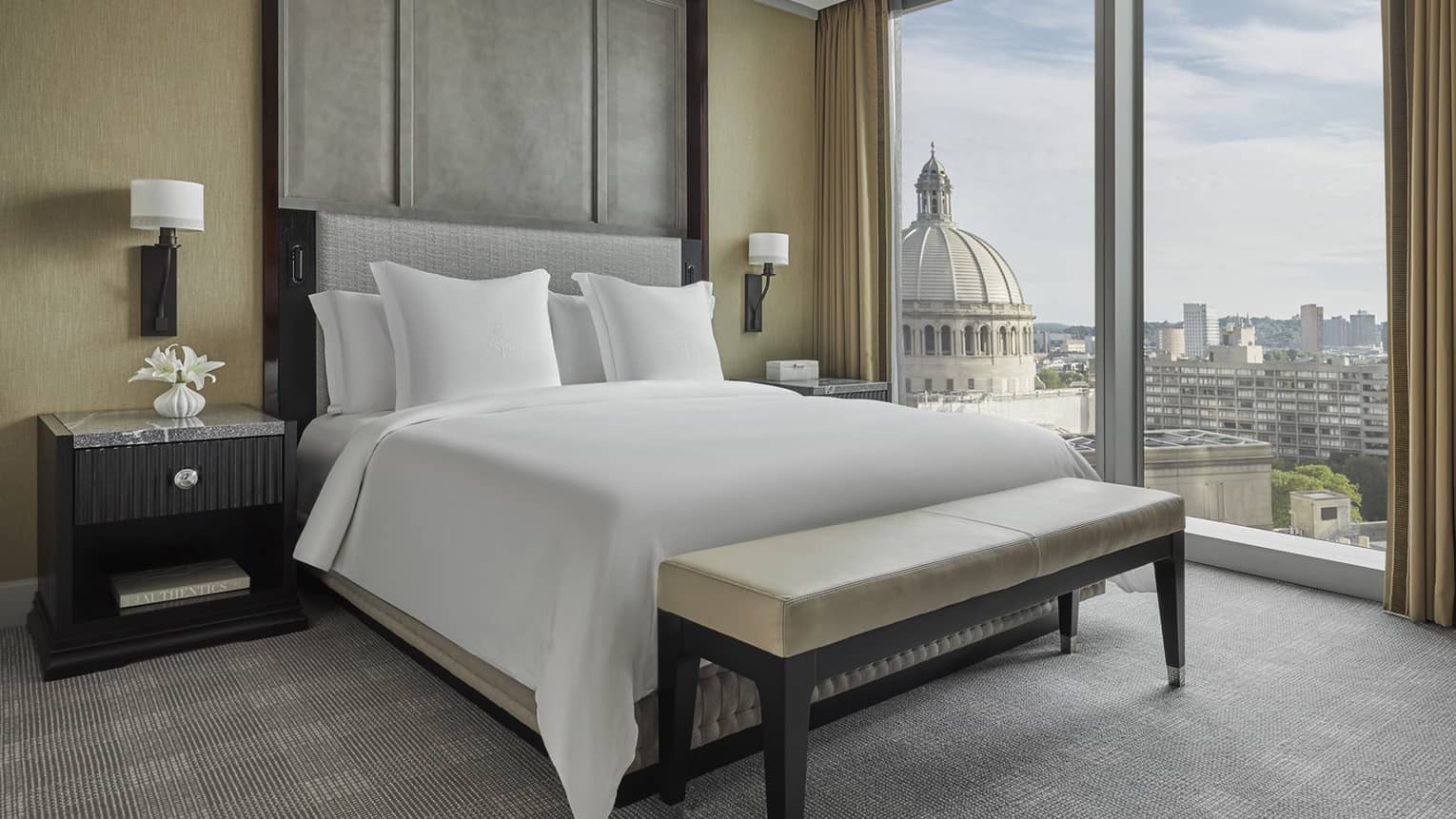 a queen bed is next to floor to ceiling windows in a suite at four seasons hotel boston one dalton