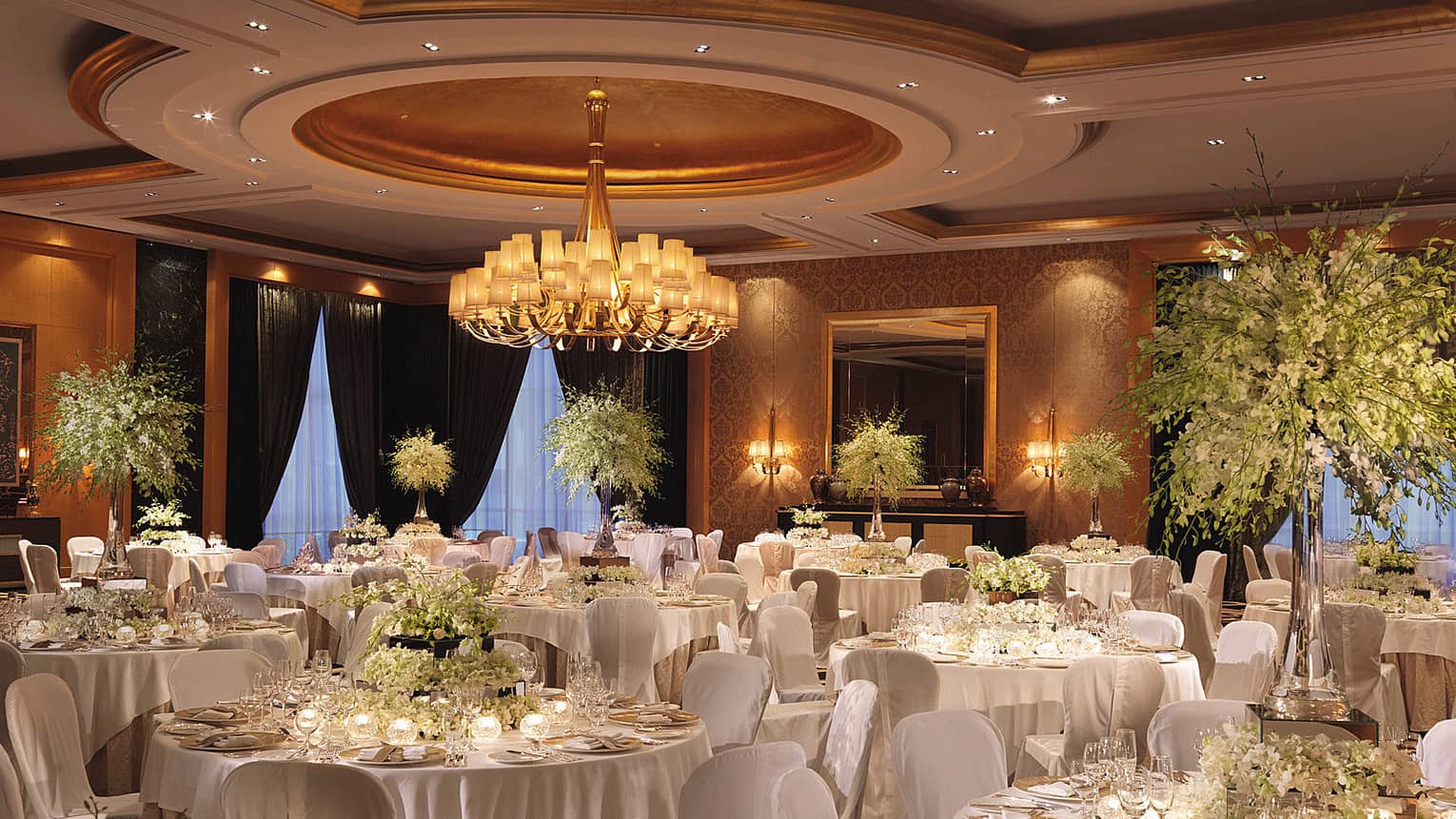 Banquet dining tables with candles, tall floral arrangements in ballroom
