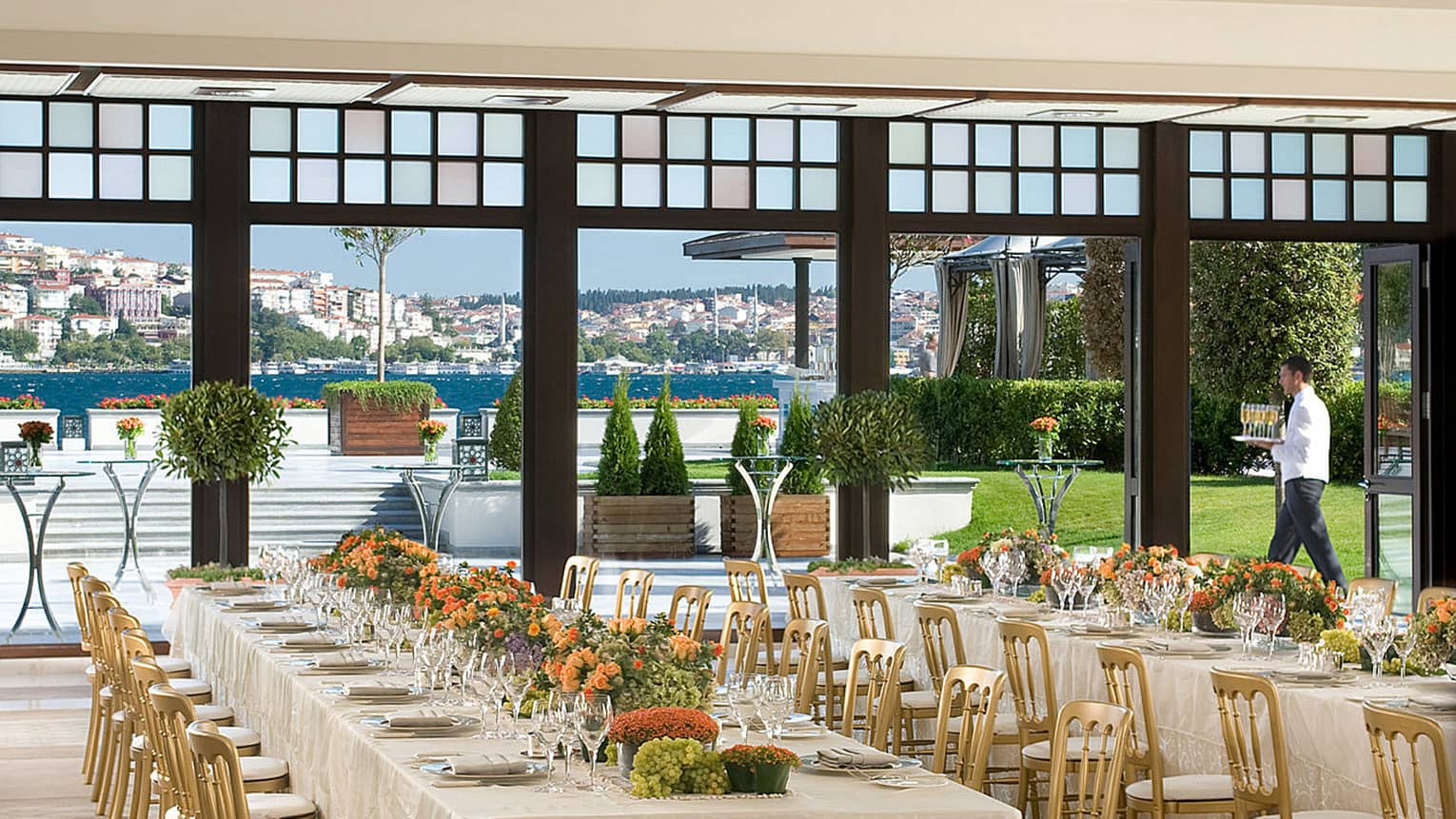 Bosphorus Ballroom long banquet tables with gold chairs under chandeliers, near open wall to terrace