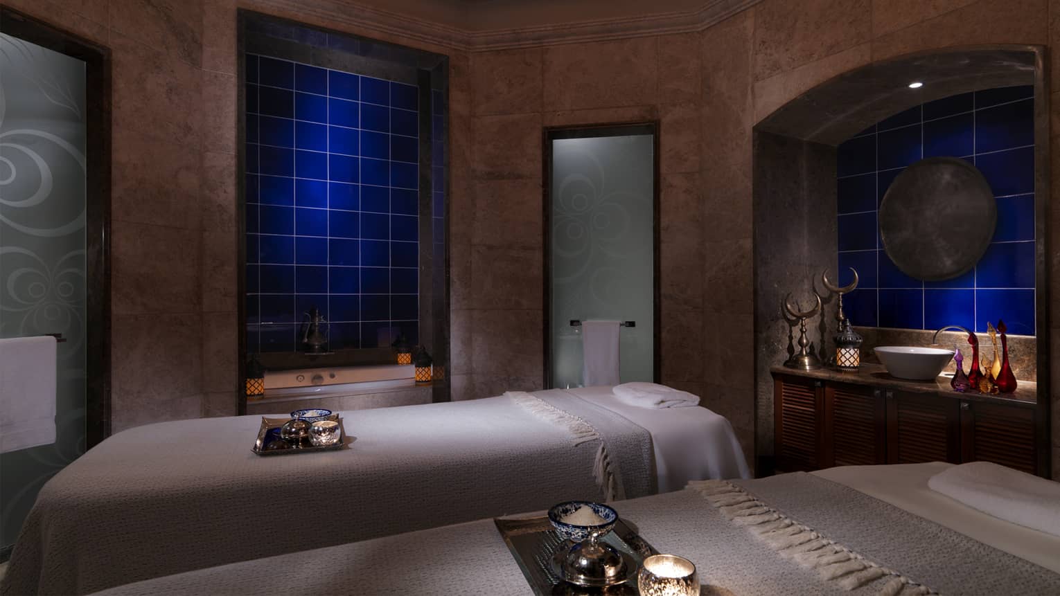 Couples massage beds in dimly lit spa treatment room with candles