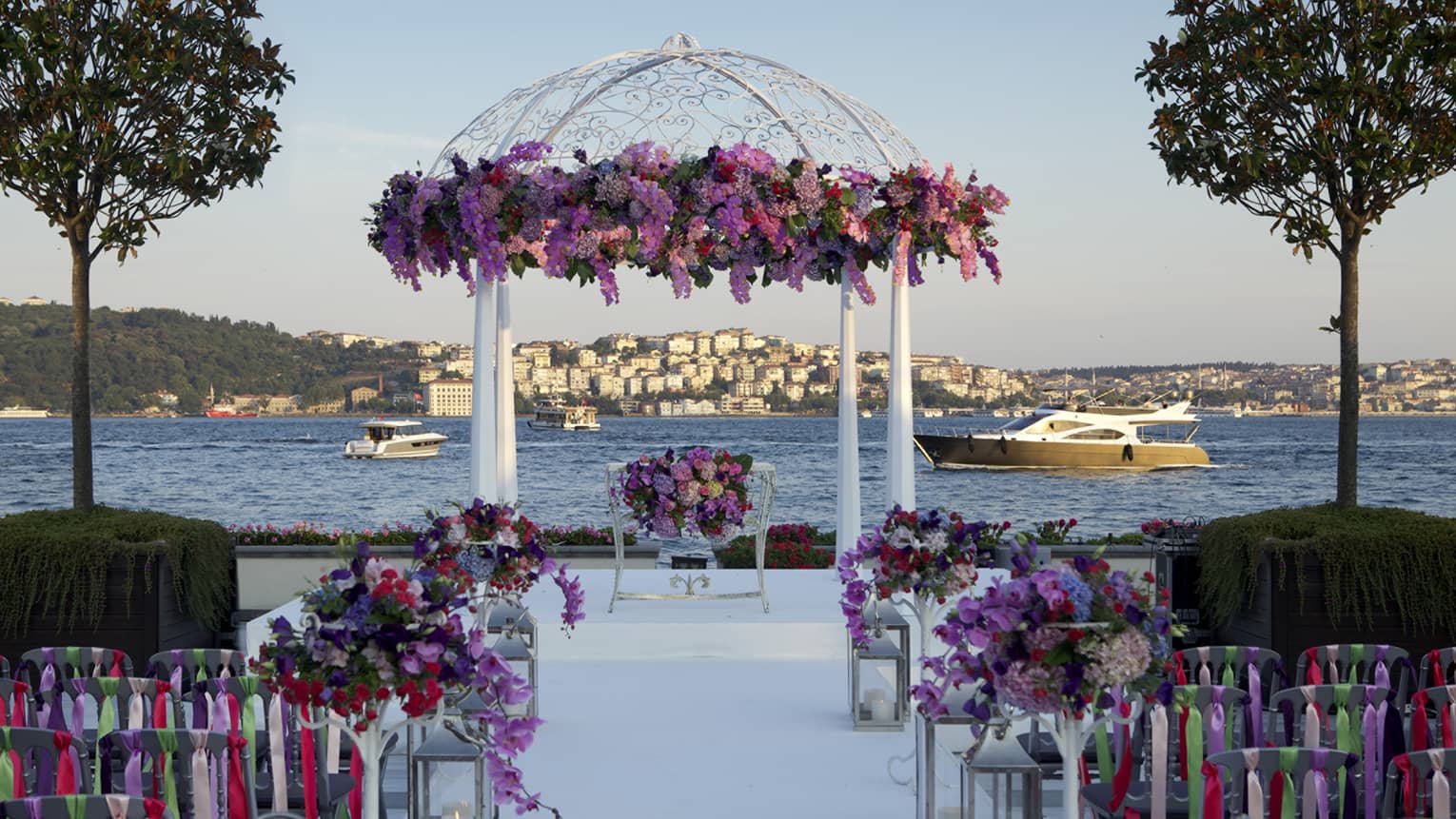 Wedding ceremony set up, rows of chairs face altar with pink and purple flowers in front of sea