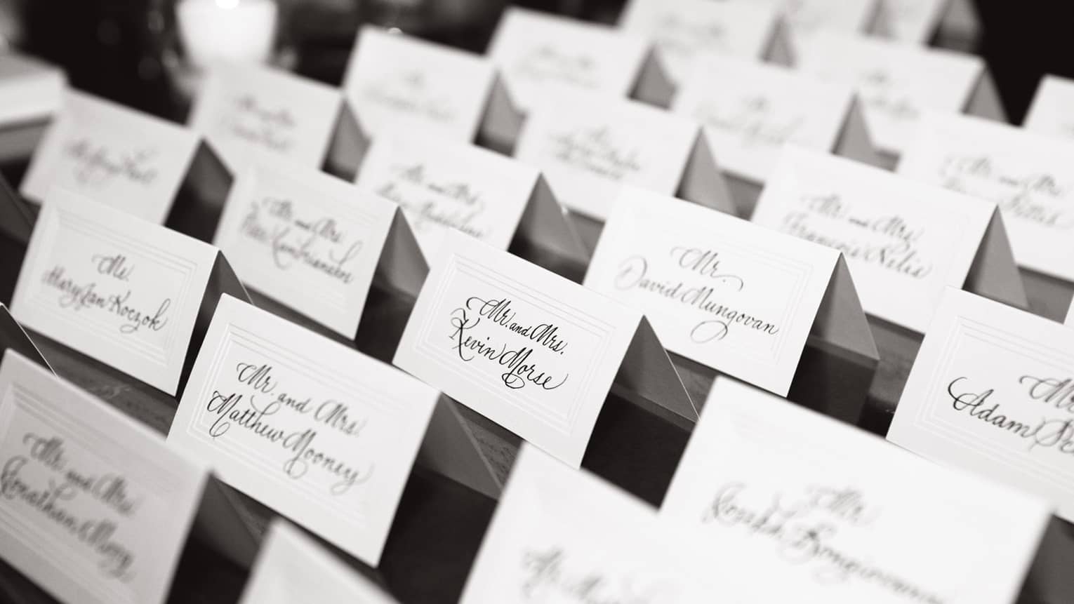 Rows of wedding place cards with guest names on event table