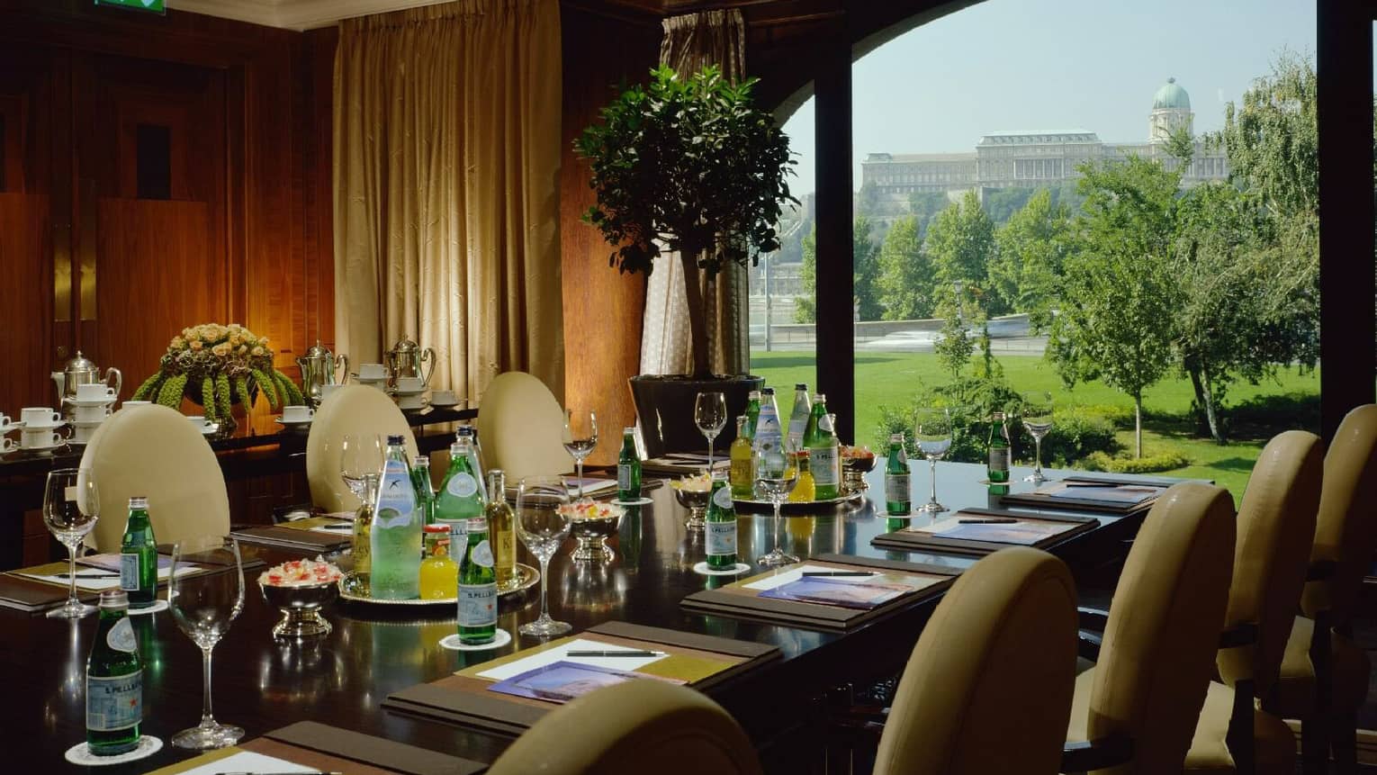 Meeting room with wooden walls, executive table with bottles of water, large window overlooking trees