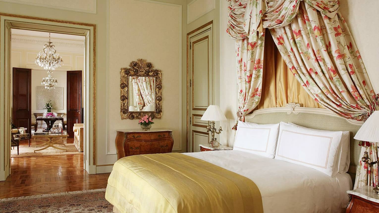 La Mansión Presidential Suite bed with gold blanket, floral drapes above headboard, door to dining room