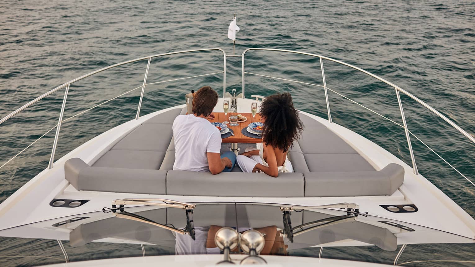 man and woman on boat enjoying a meal and glass of champagne