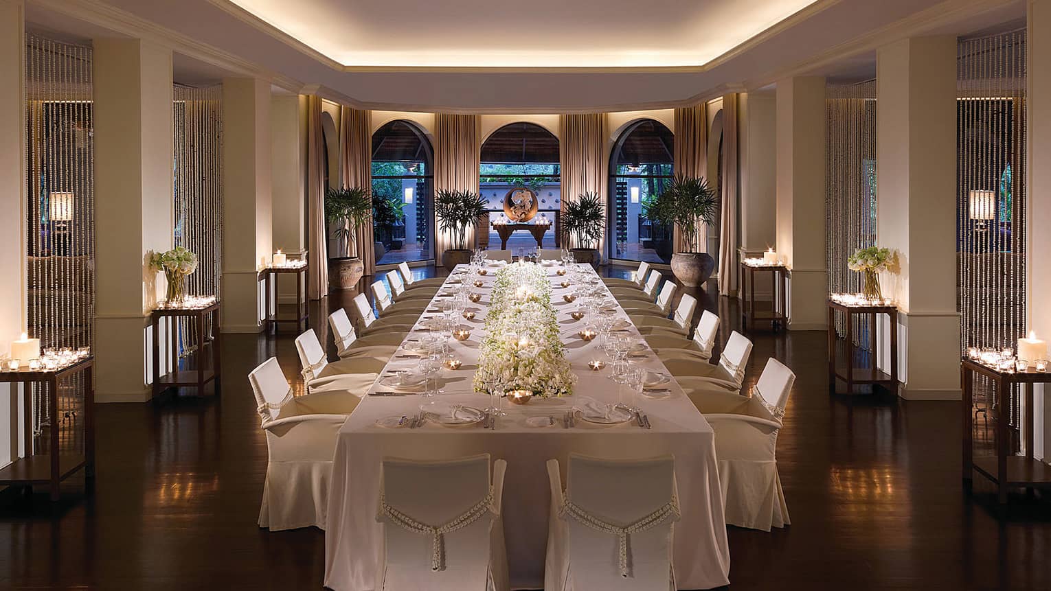 Long banquet wedding dining table with white floral centrepiece, tea lights in small copper bowls