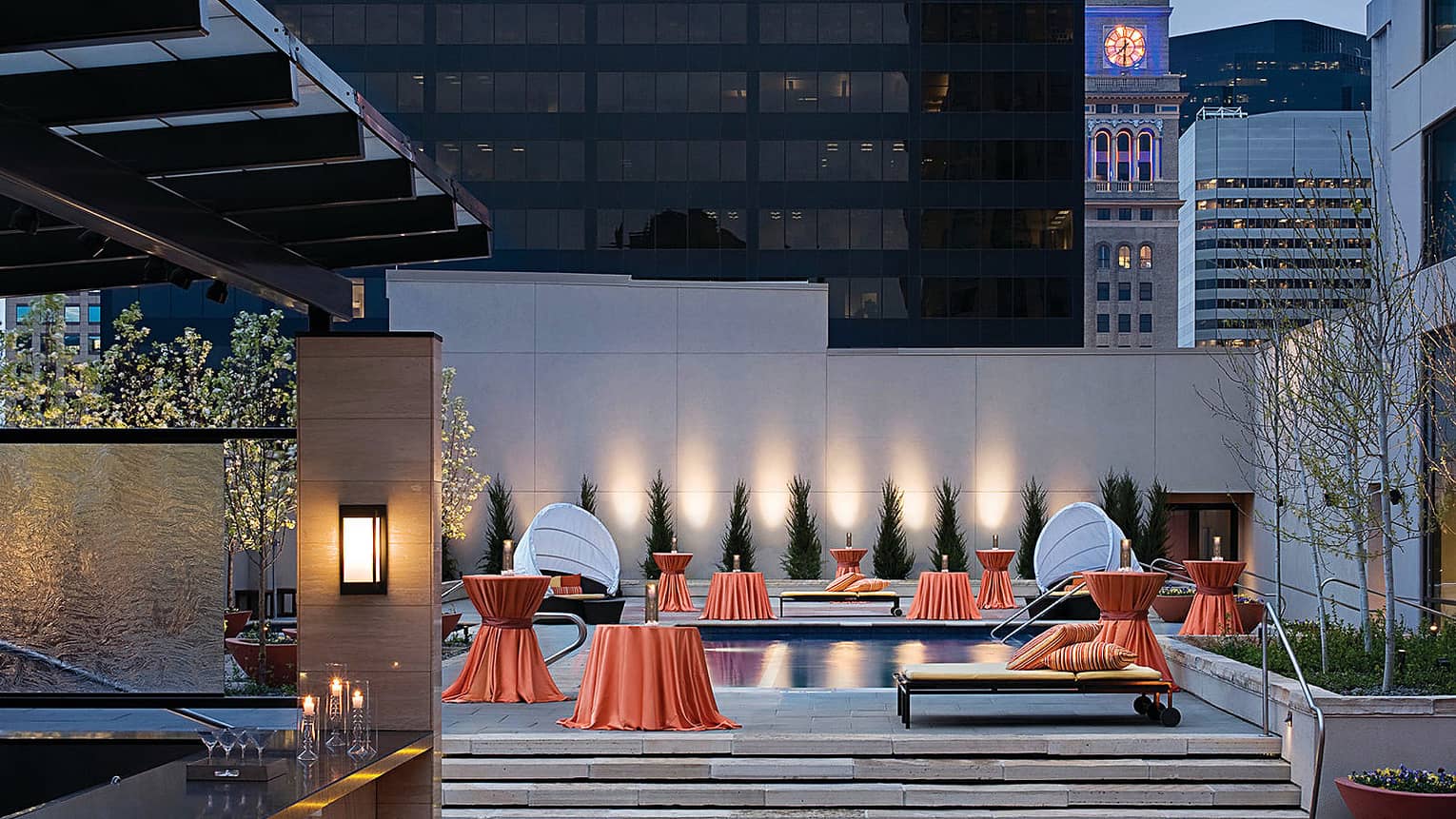 Rooftop bar, orange linens over small tables around outdoor pool