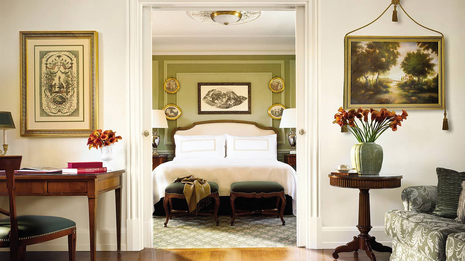Four Seasons Executive Suite desk, chair by bedroom doorway, bed and scarf across green footstools