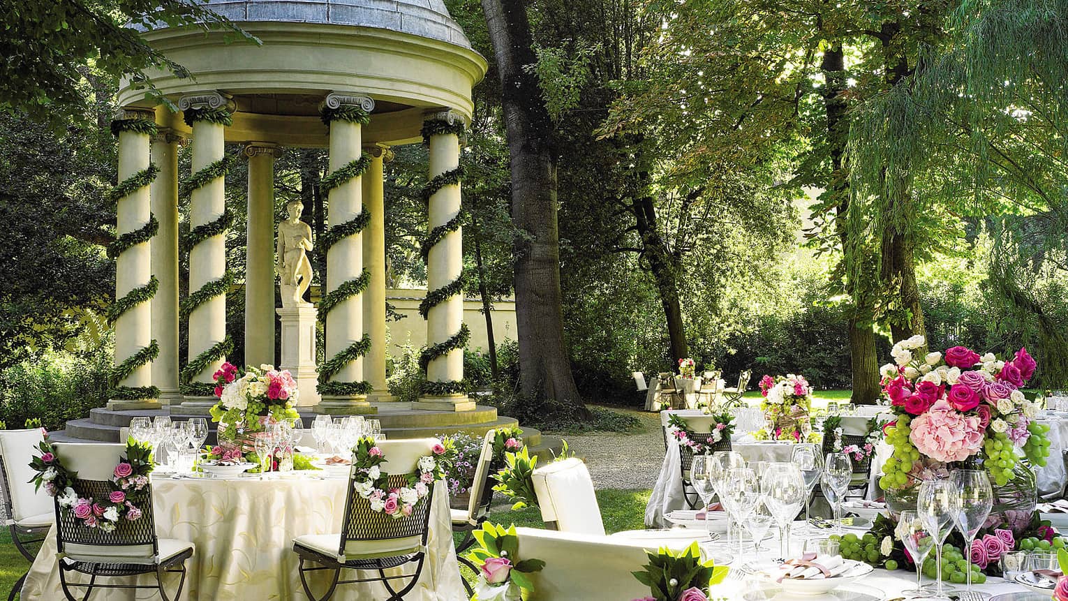 Garden reception, round, flower covered banquet tables by gazebo with white pillars