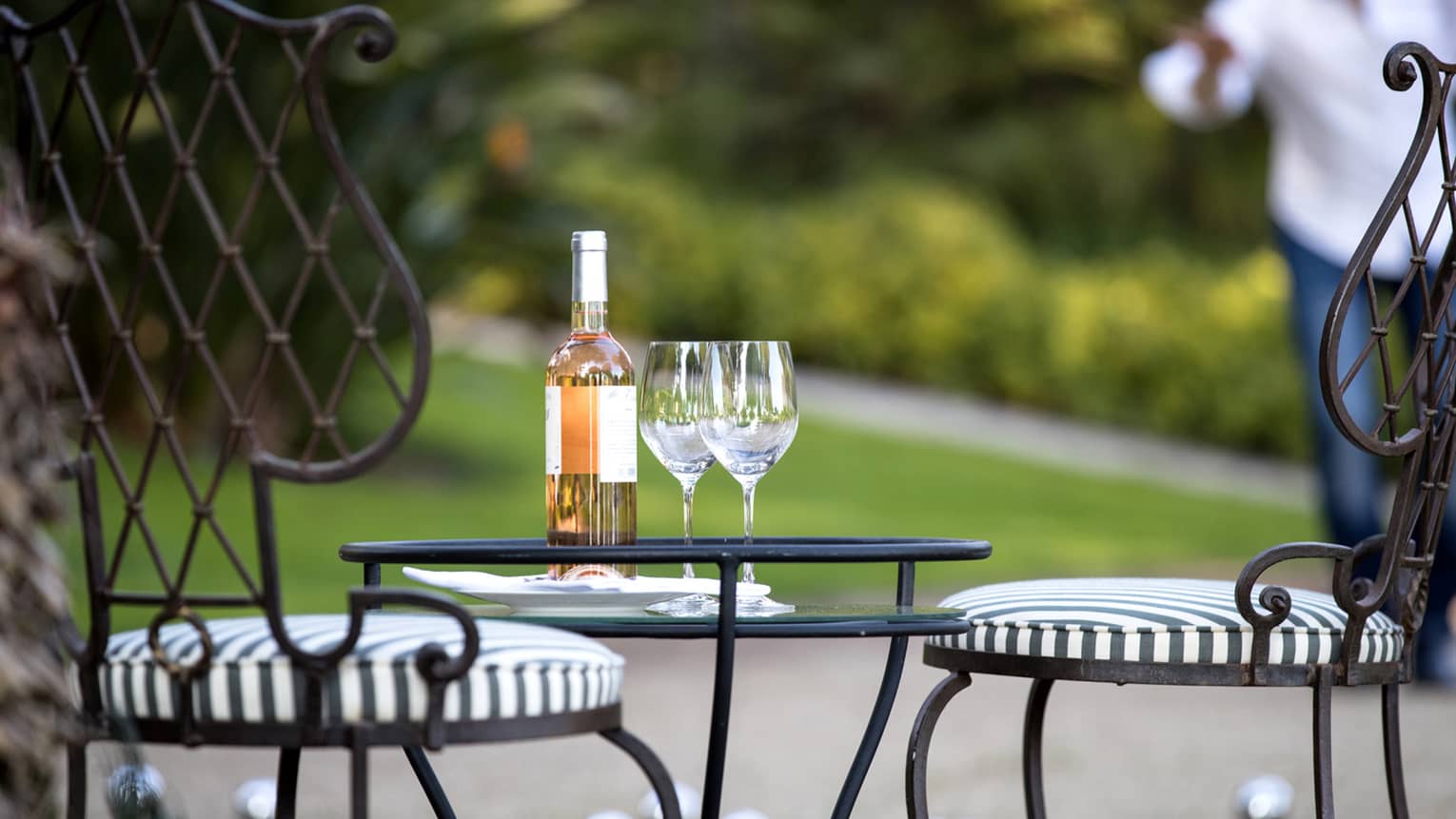 Close-up of bottle of wine, two wine glasses on iron patio table