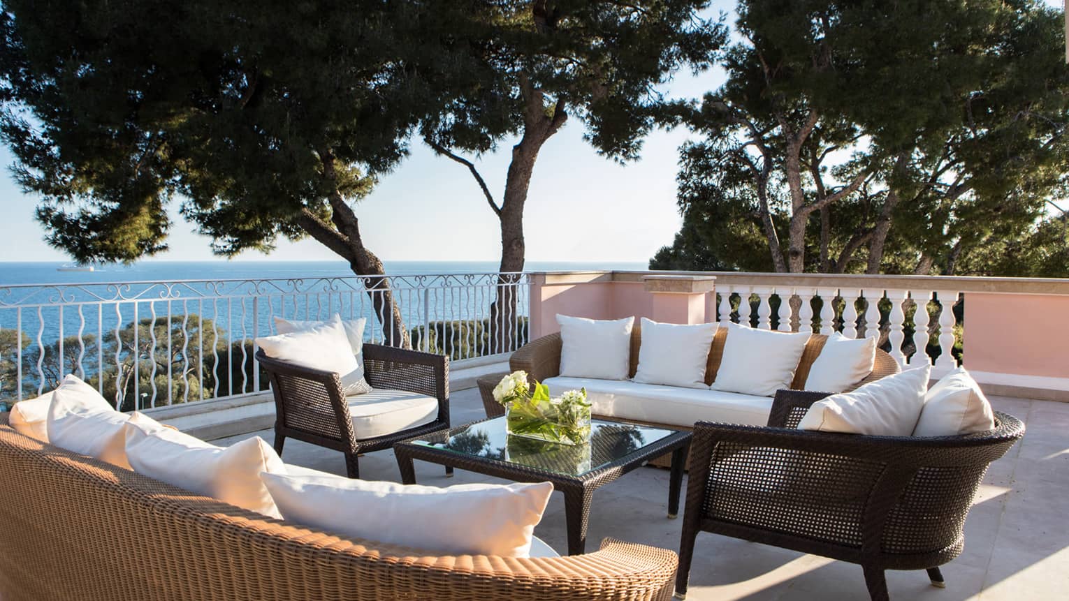 Plush patio sofas, chairs on veranda by trees, Mediterranean Sea views