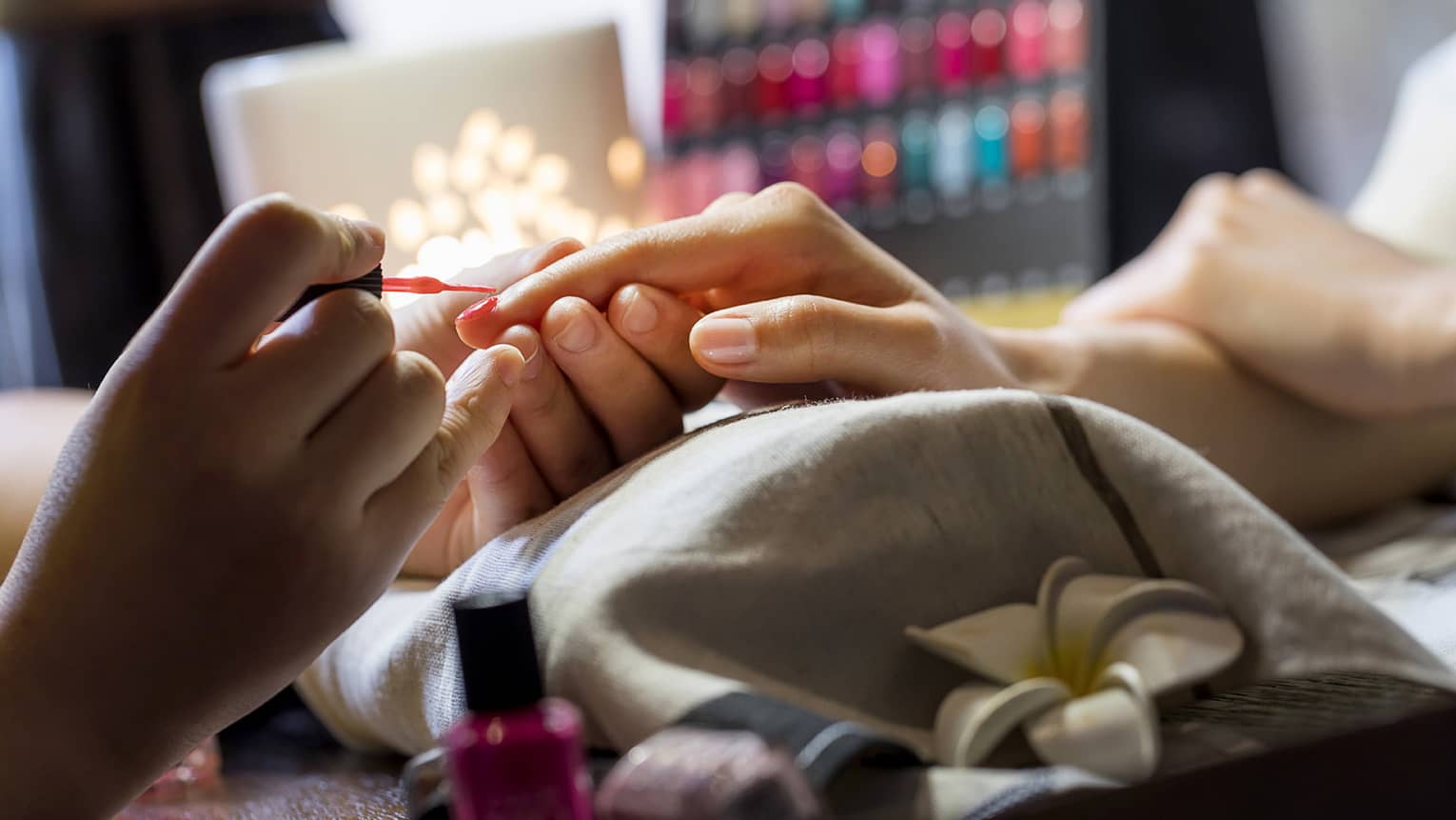 Close-up of manicure, hands resting on pillow as nails painted