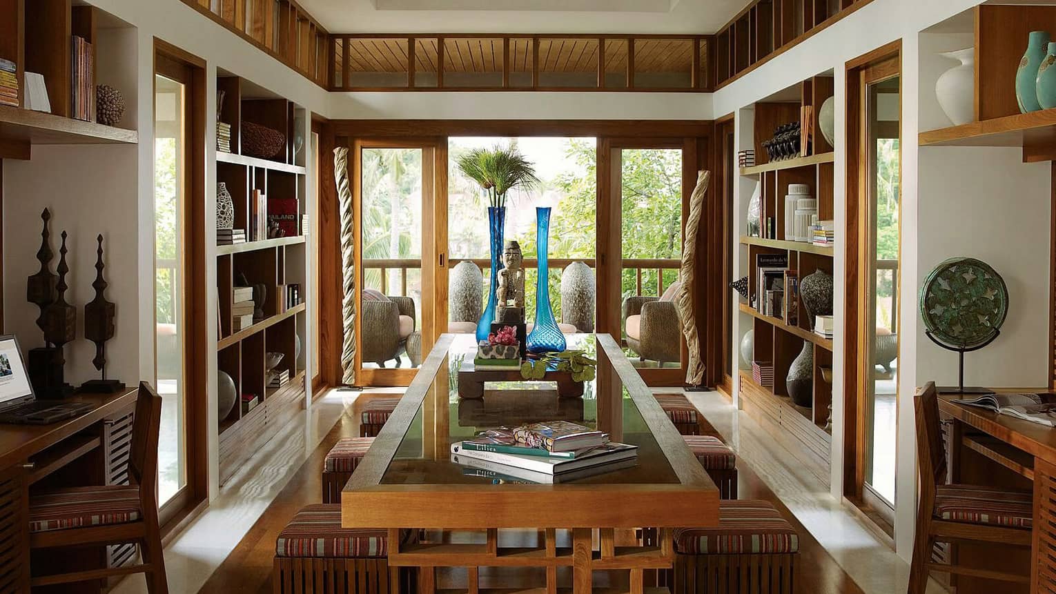 Library with wood shelves, centre table with books, decorative vases