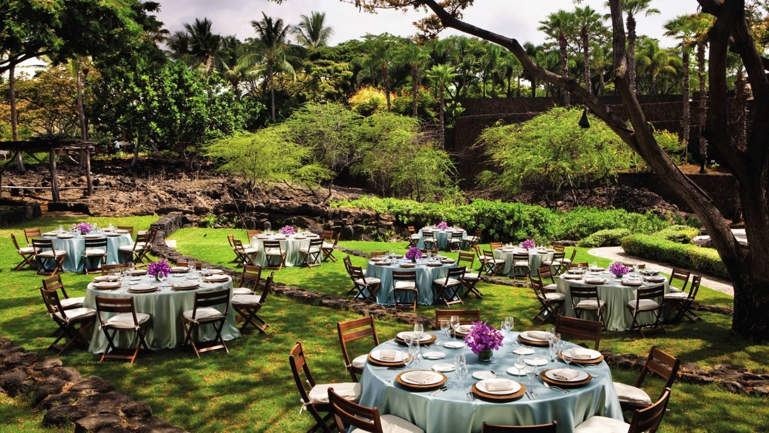 Hoku Amphitheater with round banquet tables under trees in lush garden event lawn
