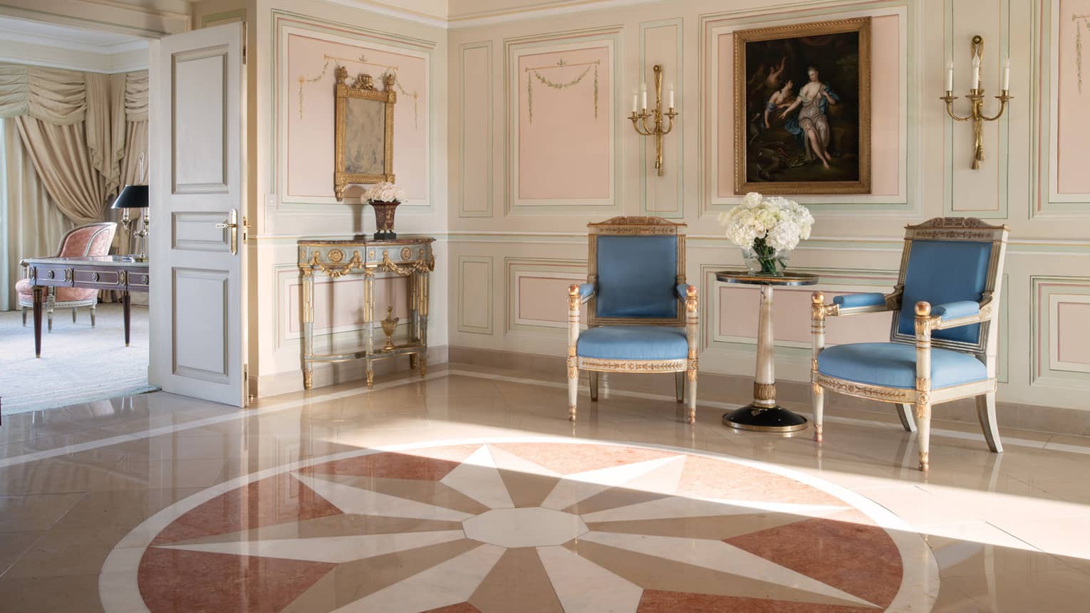 Presidential Suite lobby with large star floor motif and conversation seating with blue chairs against wall with heavy mouldings