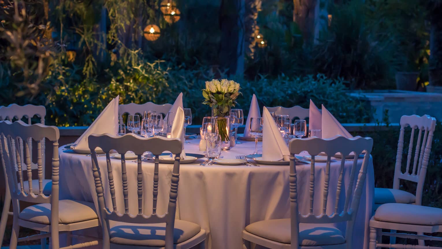 Folded white napkins on small round banquet dining table in garden at night