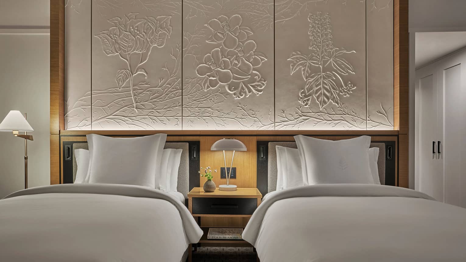 Single beds in luxurious suite below intricate wall art