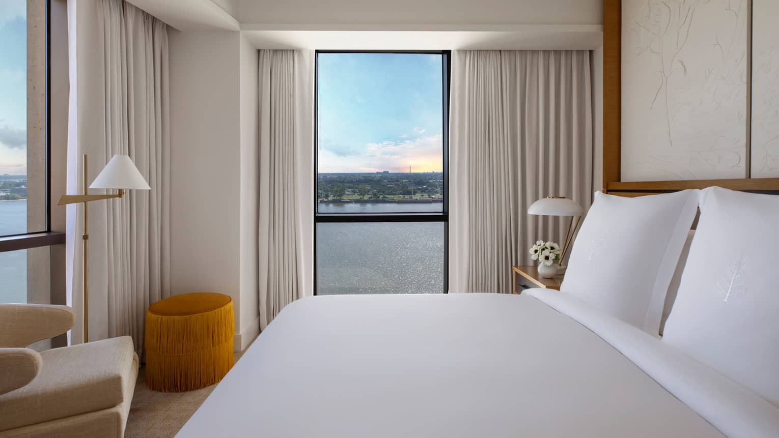Luxurious guest room at Four Seasons with a king-size bed, modern décor and a panoramic river view through large windows
