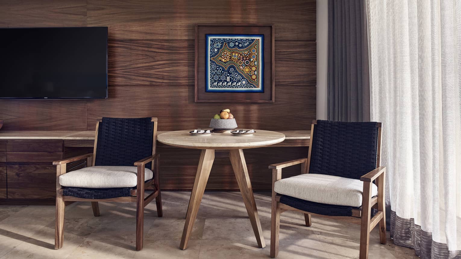 Small wooden table and two arm chairs, wooden wall and artwork
