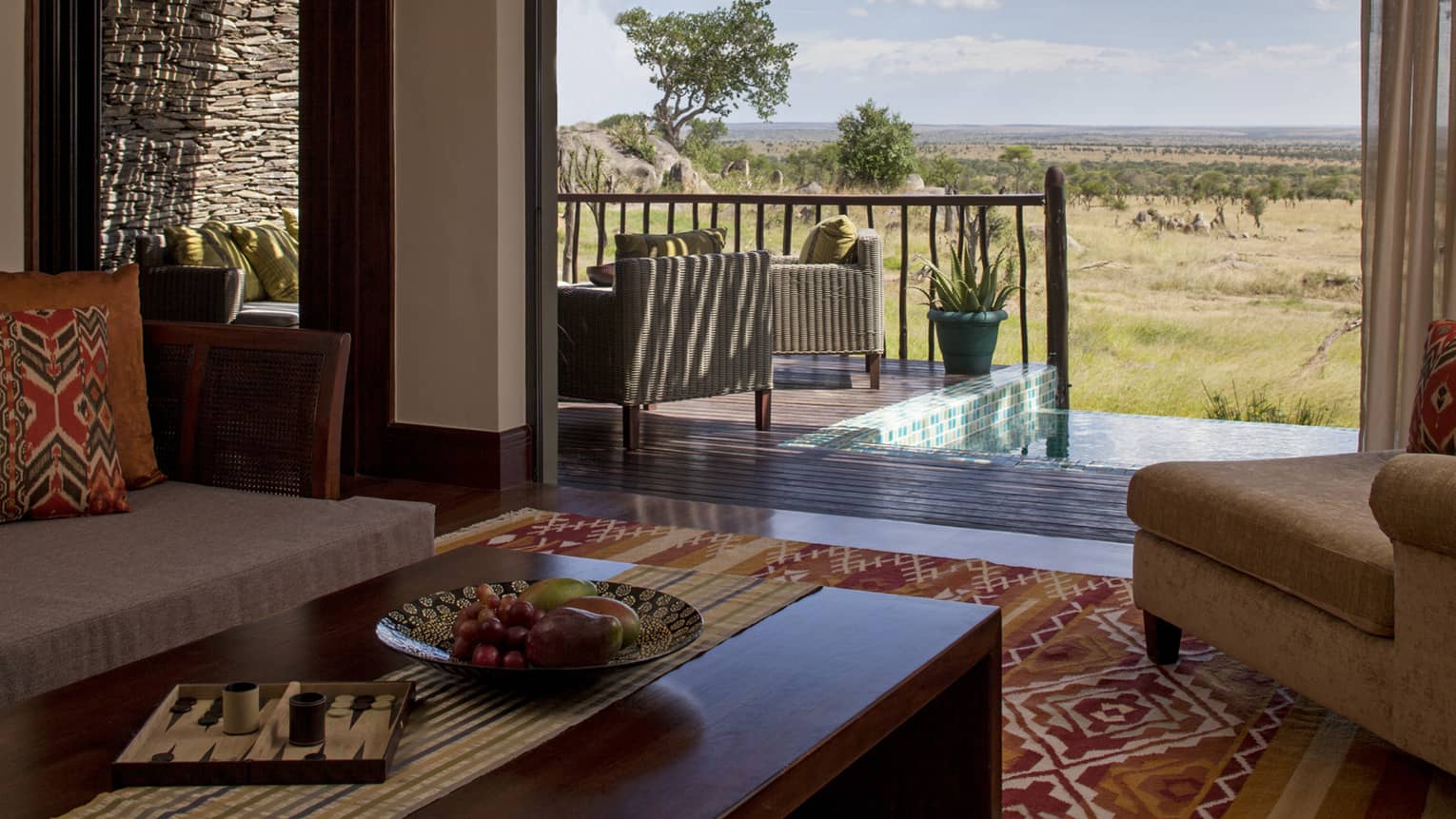 A suite decorated with earth toned couches and a rug look out onto an out at the watering hole