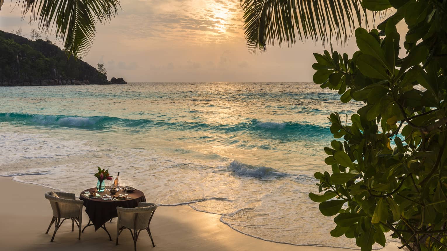 Romantic couples dining table set up on Seychelles sand beach at sunset 