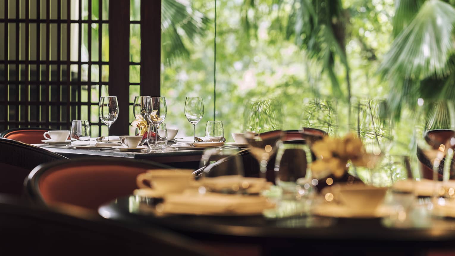 Close-up of empty wine glasses, dishes on restaurant table by sunny window