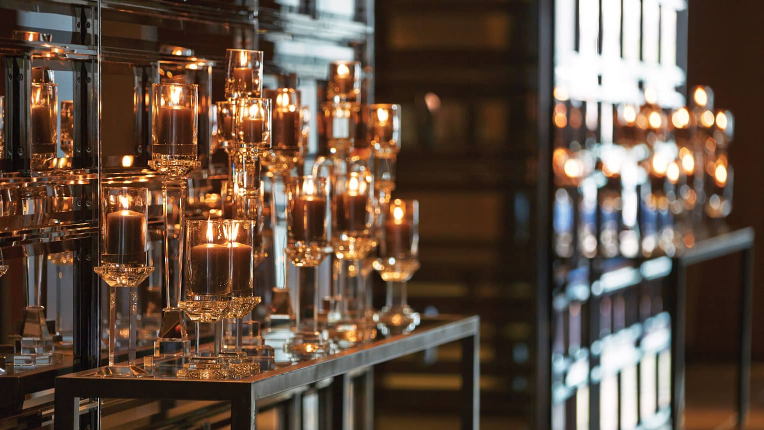 Glowing candles in glass holders displayed on shelf