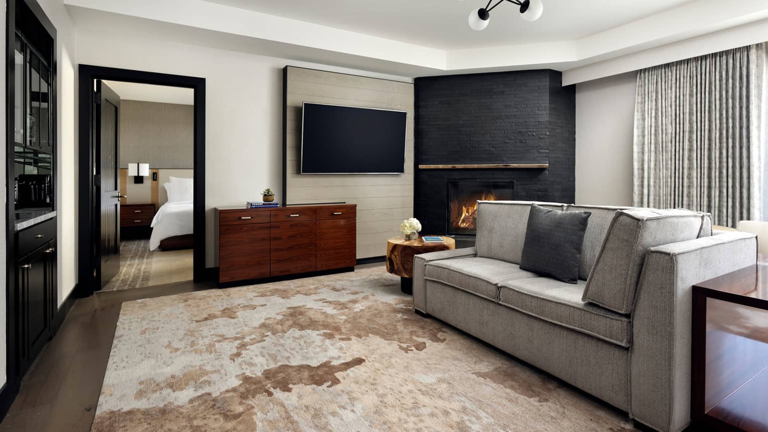 Living room with grey sofa, area rug, slate fireplace, contemporary ceiling light