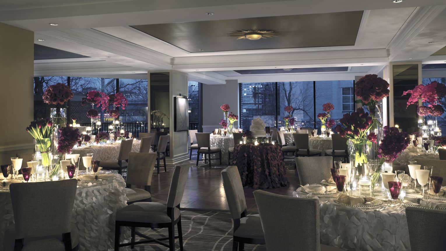 Seasons dining room wedding banquet setting at night with candle-lit tables, fringed tablecloths, floral centrepieces