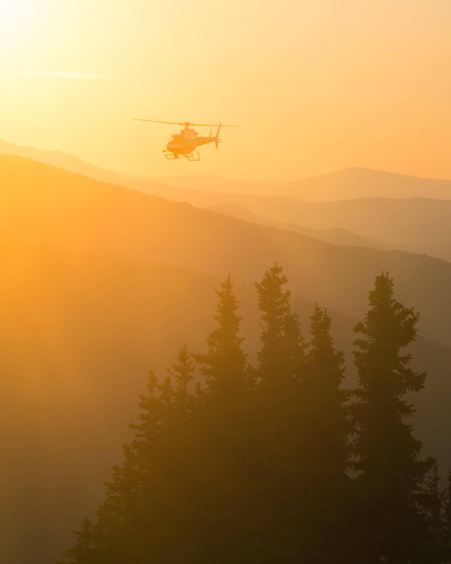 Helicopter at sunset flying over Aspen Mountain in the Elks Mountain range