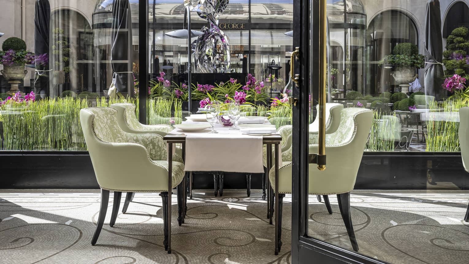 Seating area in L'Orangerie restaurant in a brightly lit room with a wall of windows