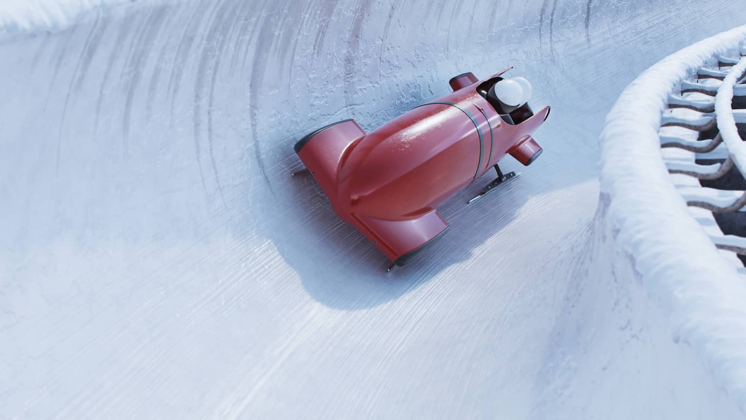 Front view of a bobsleigh zipping around a corner on a concave icy track, the helmets of two riders visible from the cockpit.