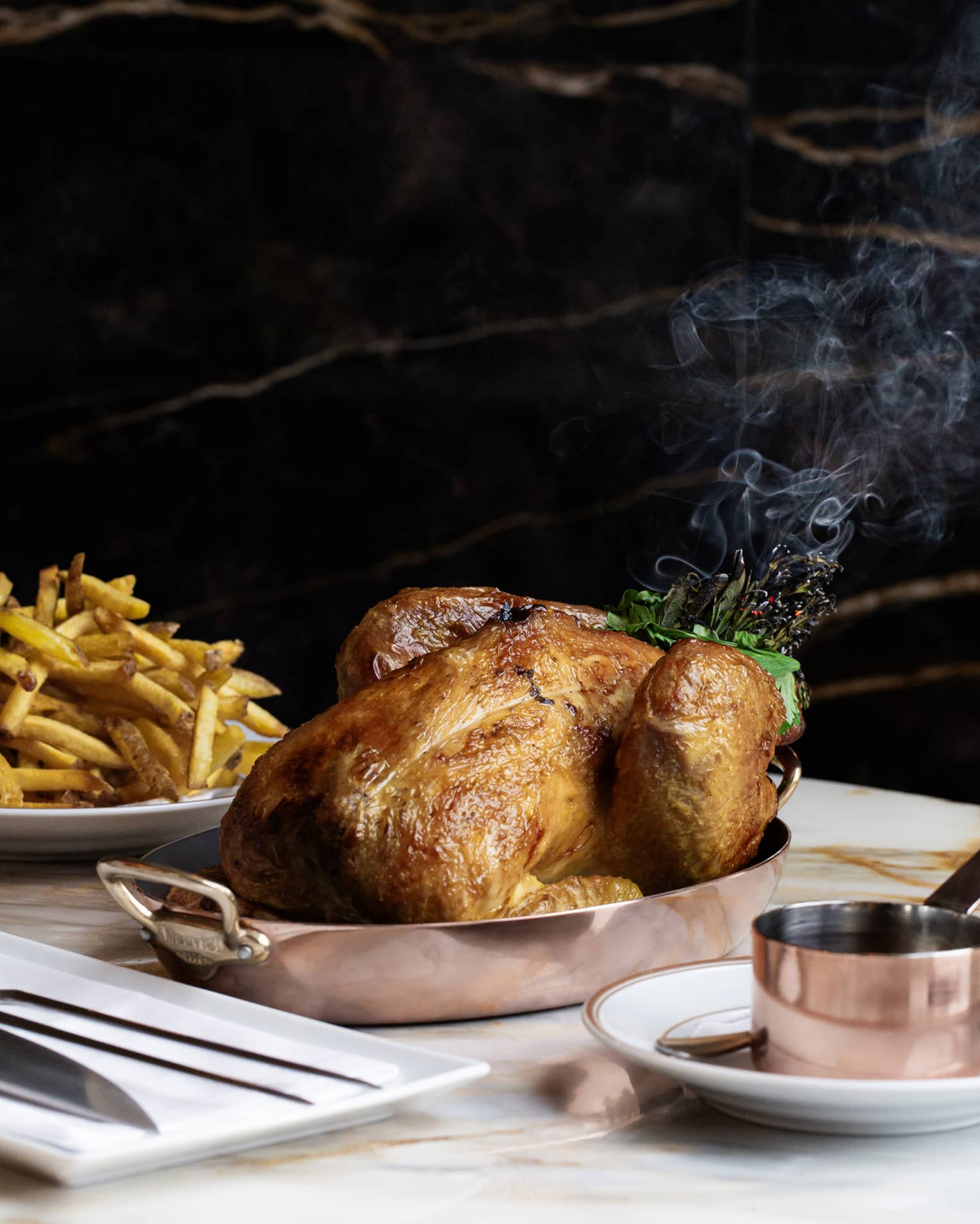 Golden brown whole roasted turkey in copper chafing dish beside plate mounded with French fries