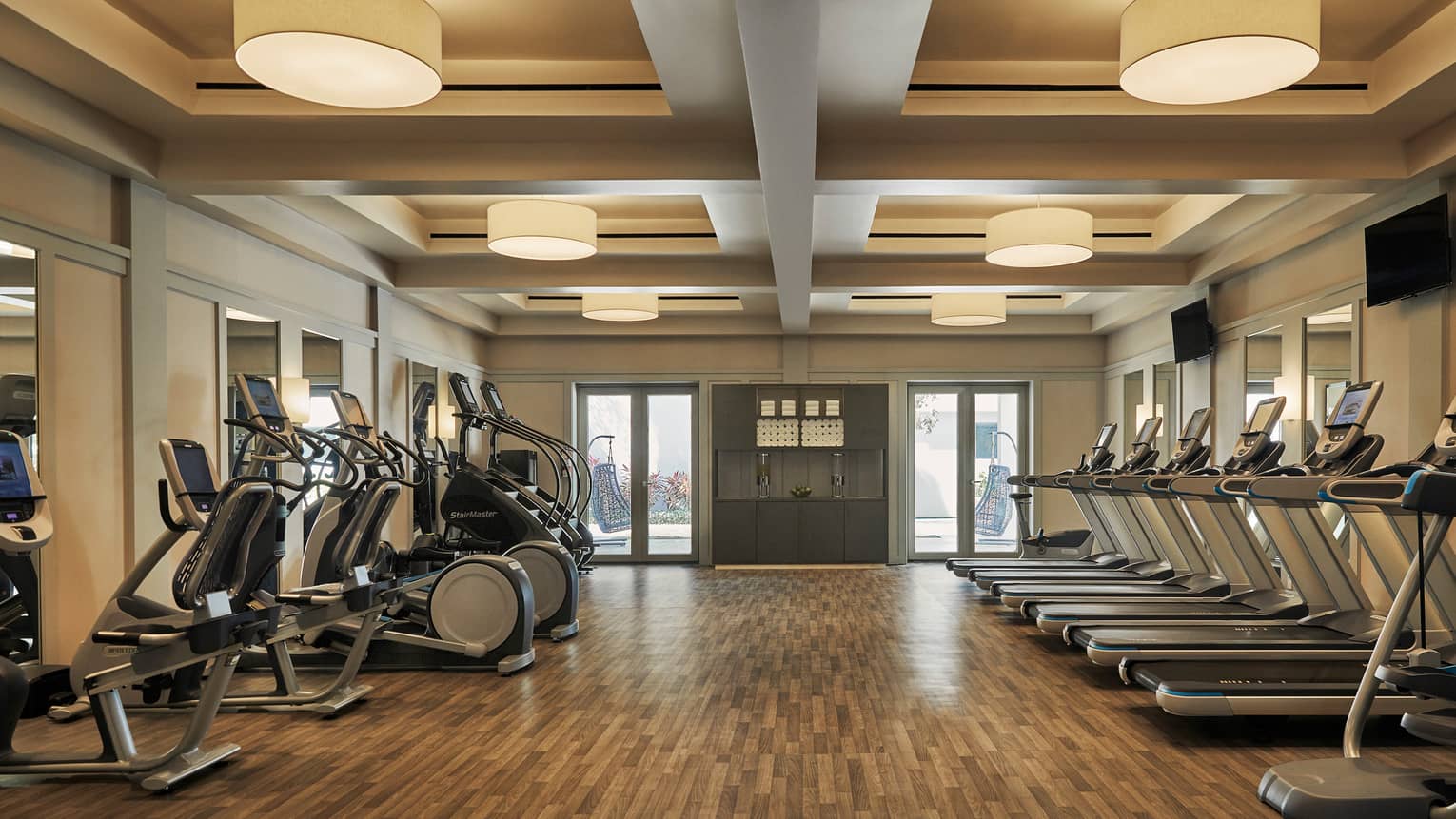 A well lit gym with cardio machines.