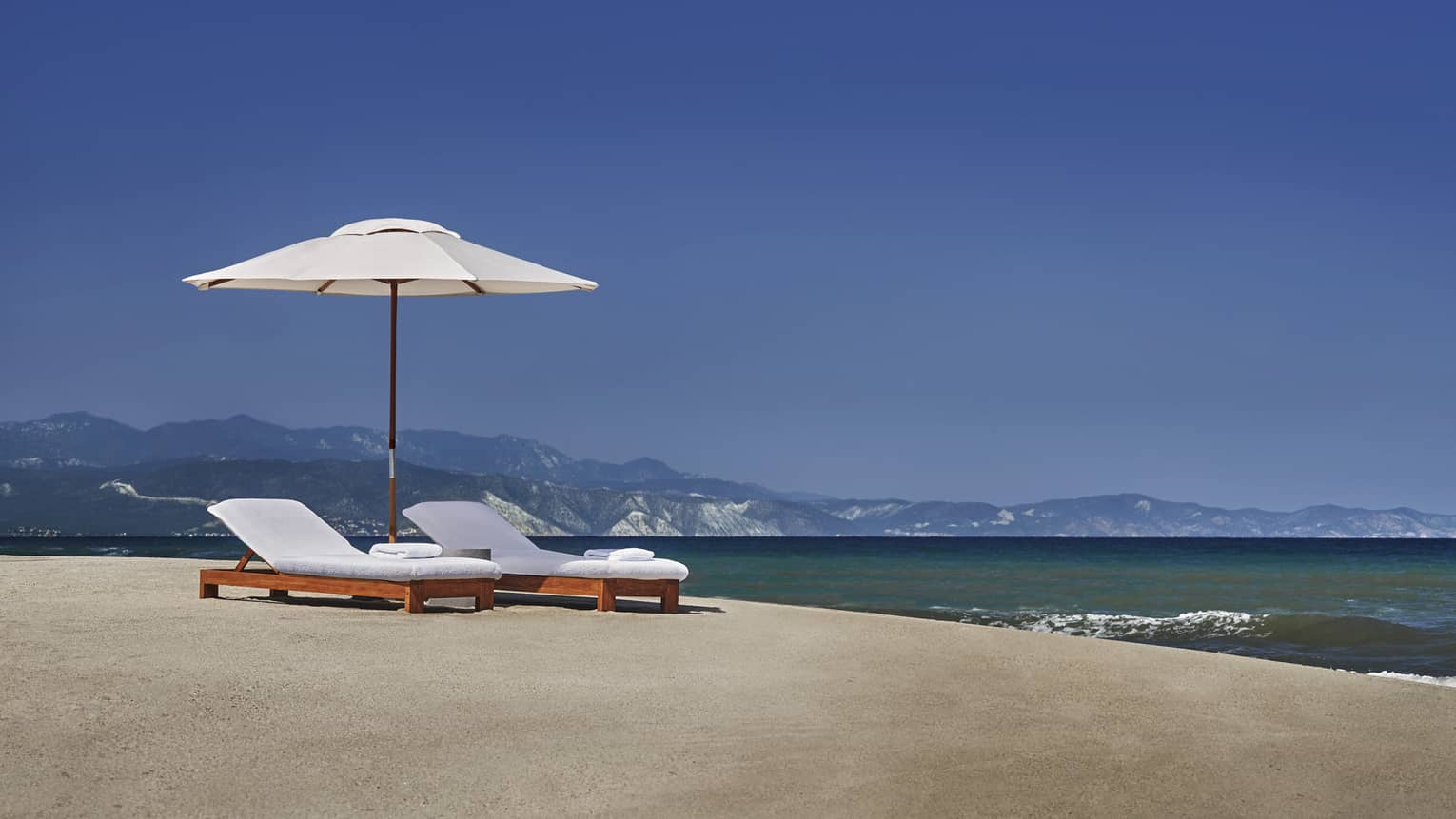 White patio umbrella, lounge chairs on sand beach