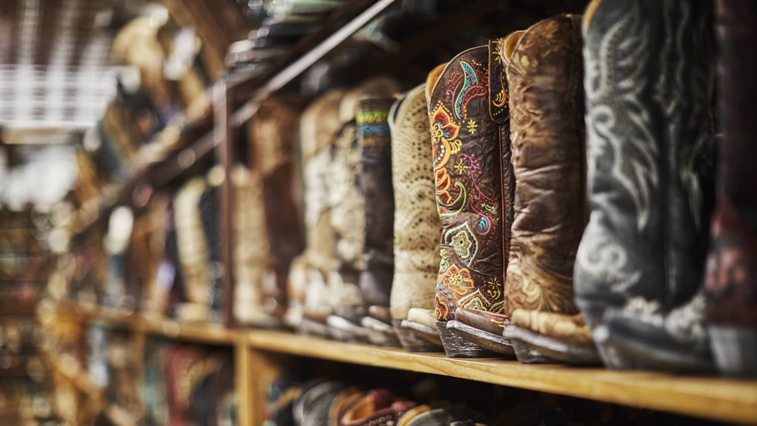 Shelves of cowboy boots of varying colours including black, brown and beige.