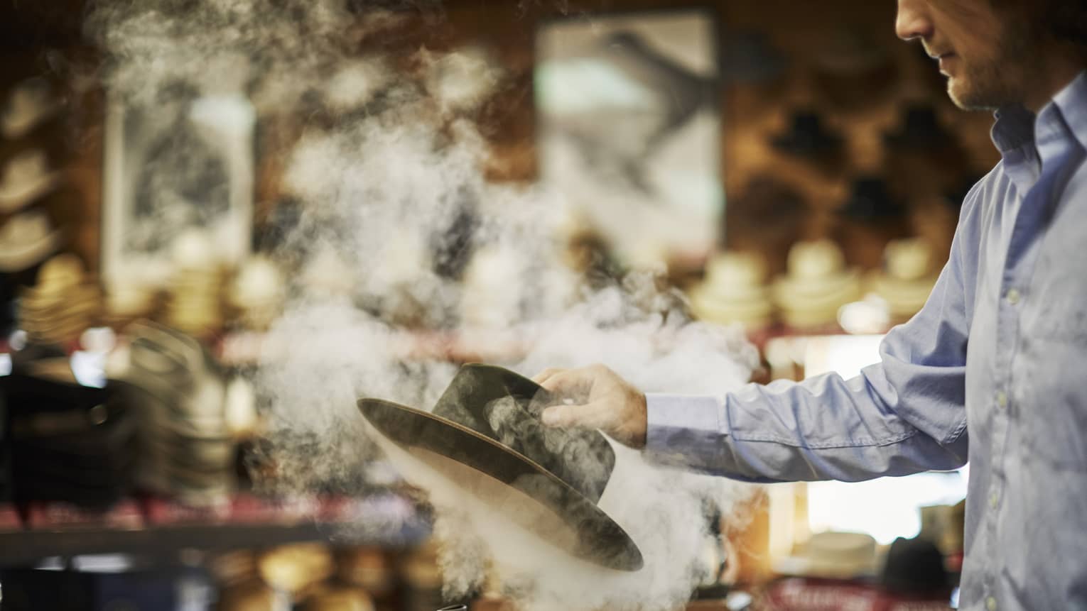 A man picking up a steaming hat.
