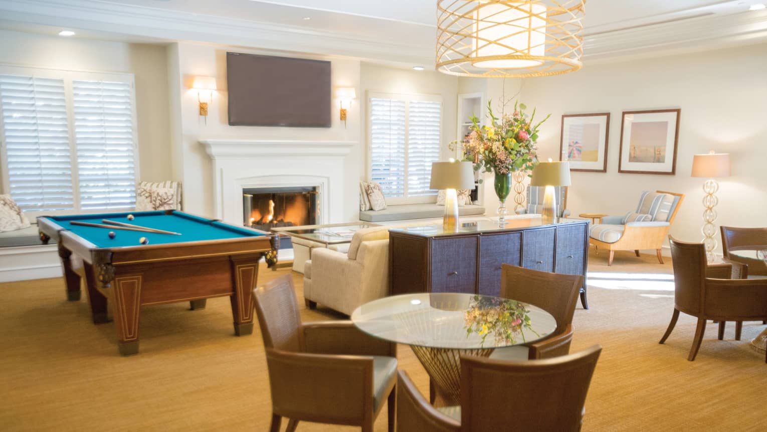Hotel recreation lounge with pool table, fireplace and sofa, round glass tables with chairs 