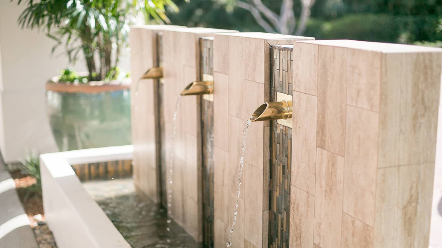 Water falls from brass spouts of marble outdoor fountain