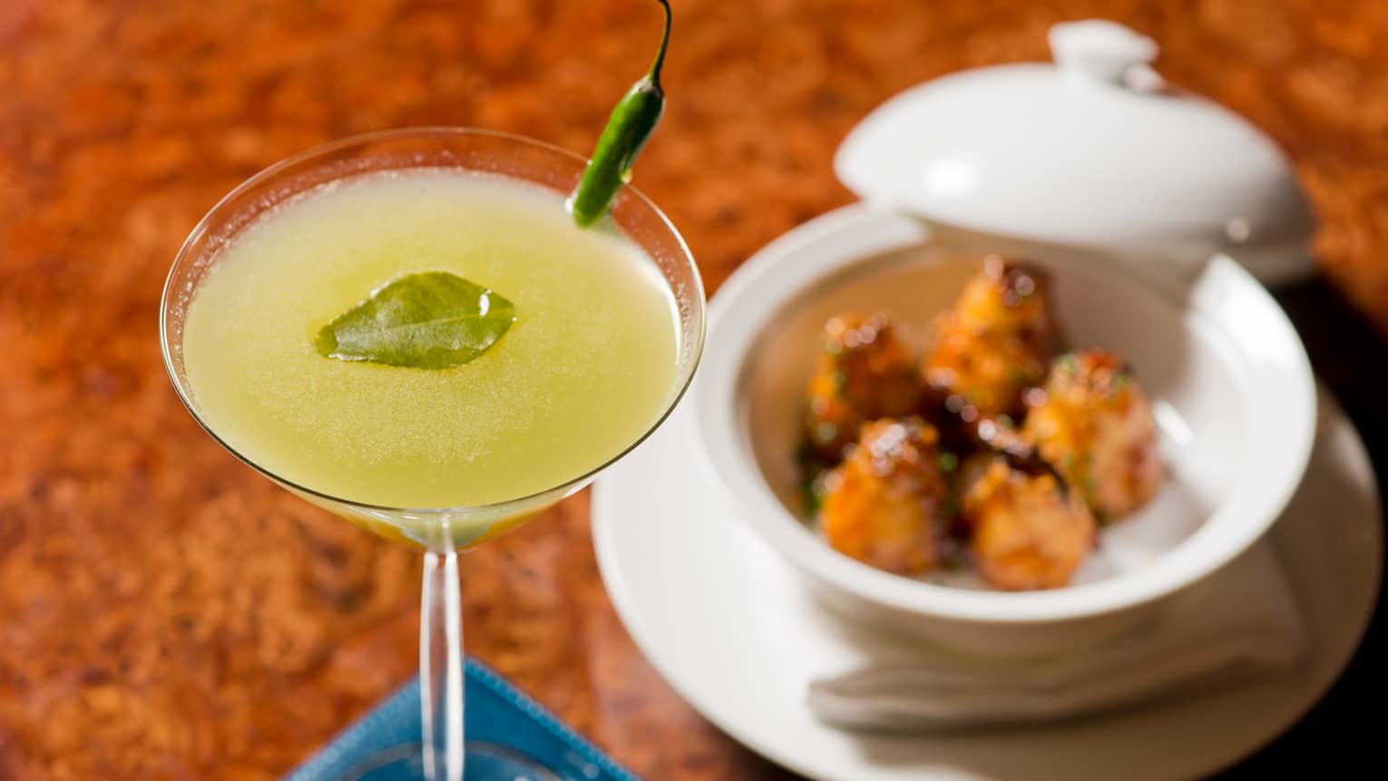 Yellow cocktail in margarita glass, handmade dumplings in white dish with lid