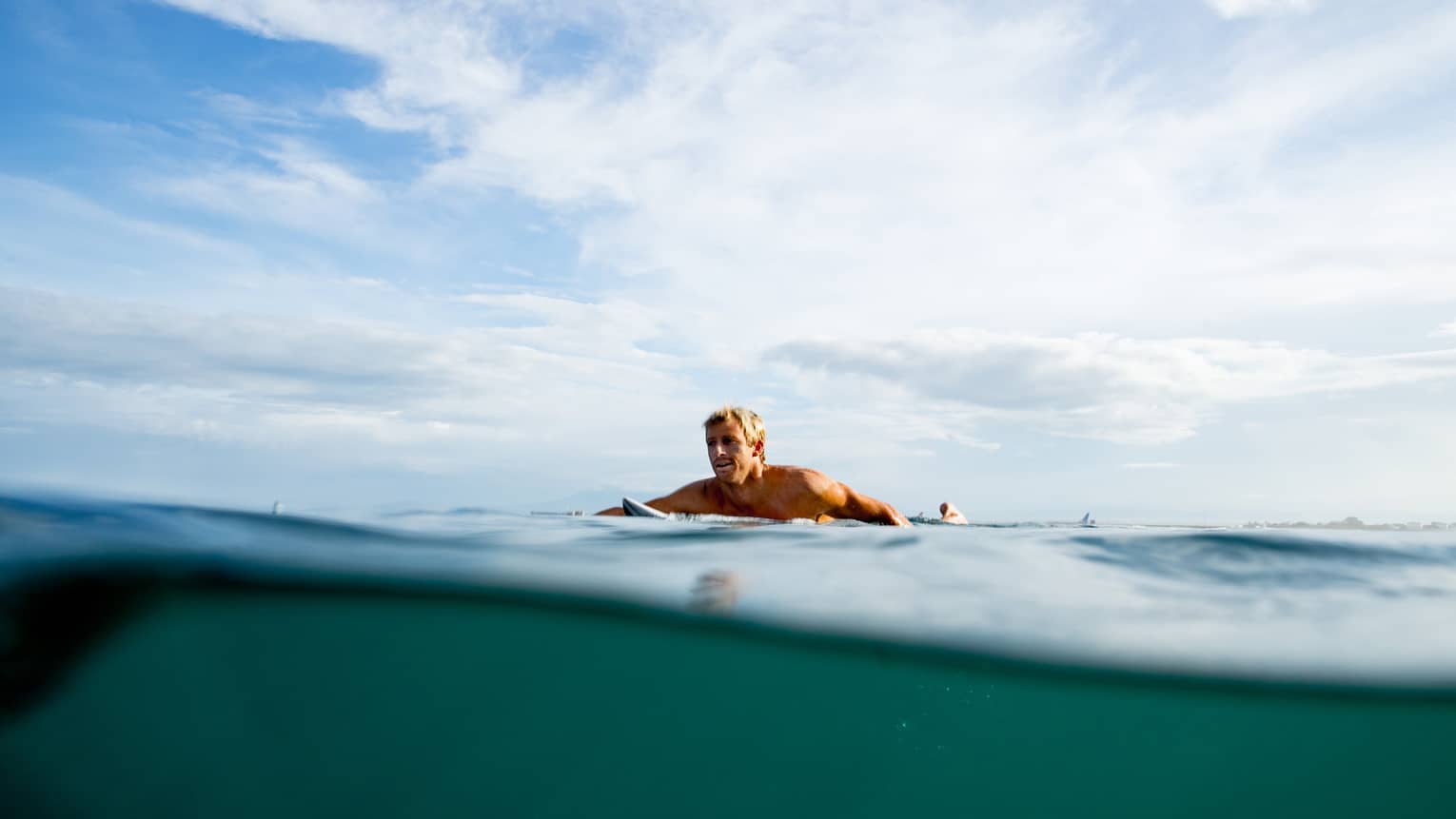 A guest swims out to surf on the water in Bali