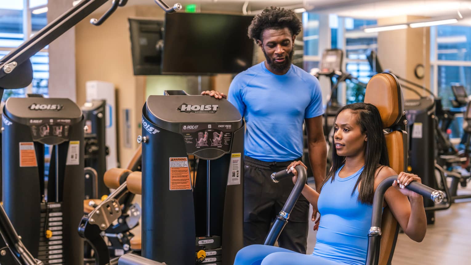 Two guests in a gym, one guest using a gym machine.