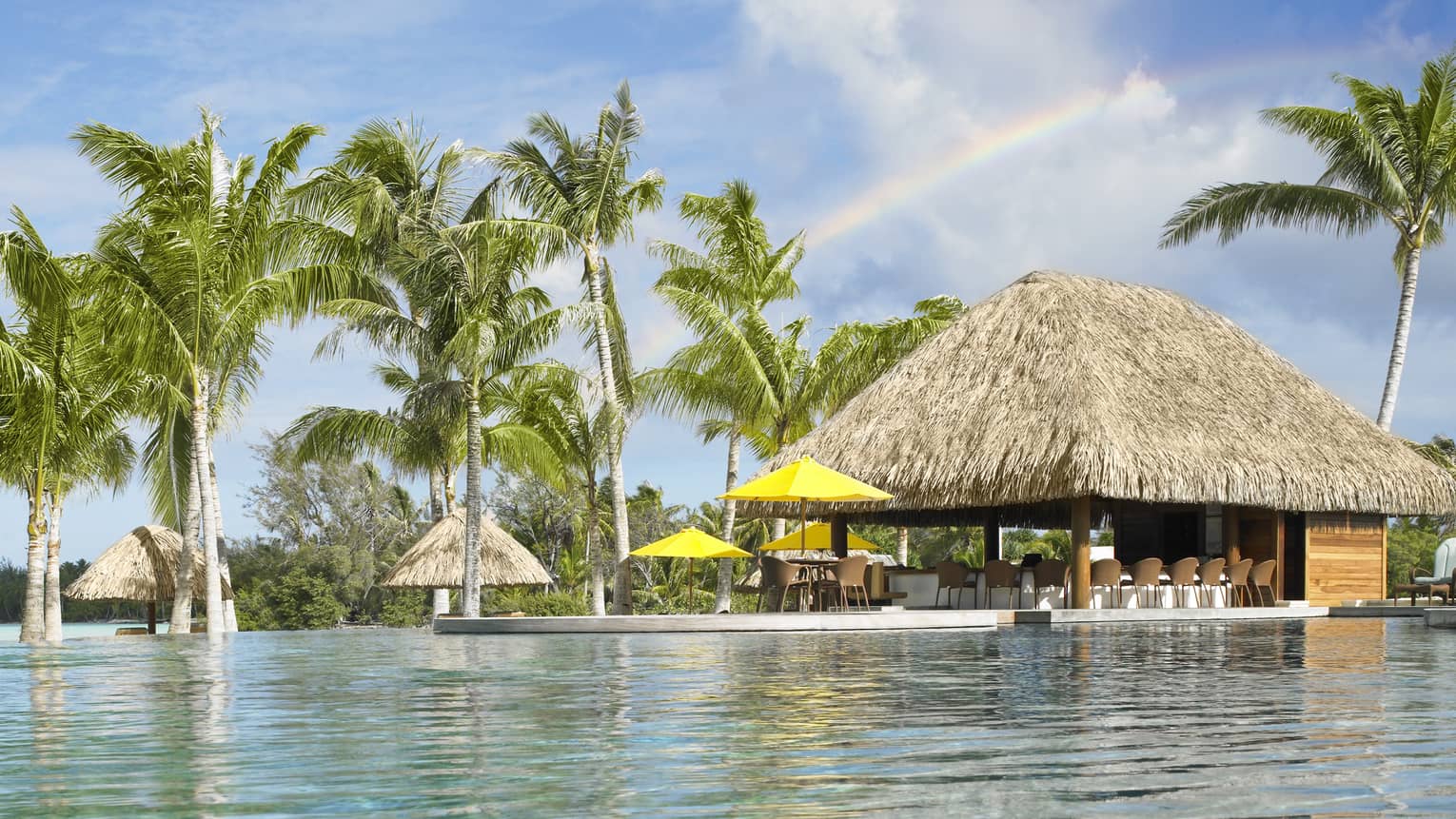 View over water to Fare Hoa Beach Bar huts and palm trees